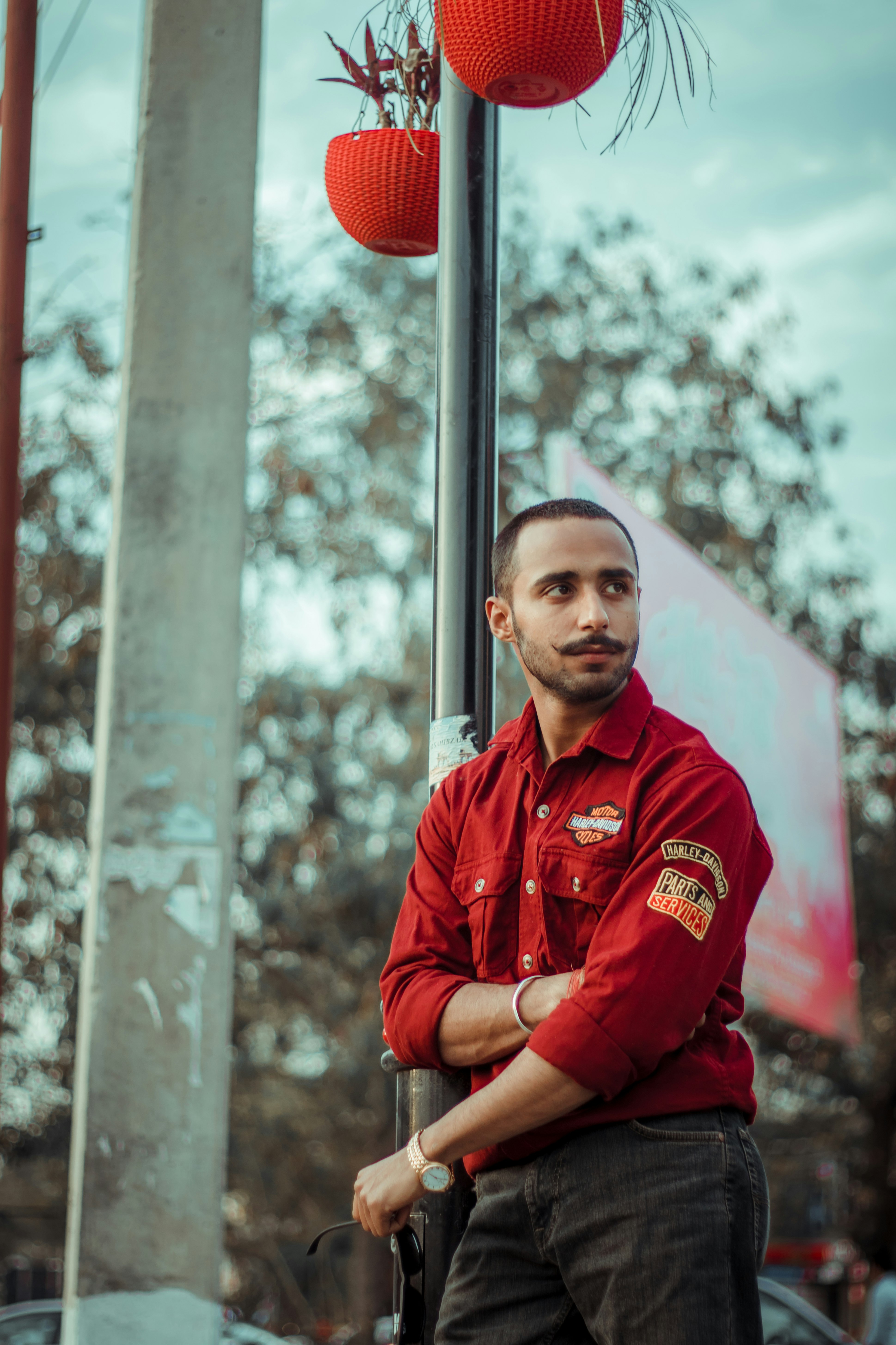 man in red zip up jacket standing near trees during daytime